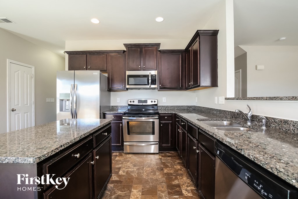 A kitchen with dark brown cabinets and granite countertops.