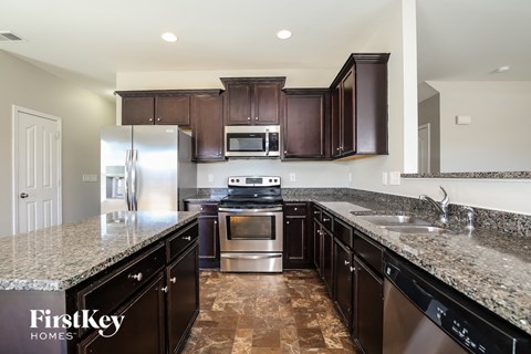 A kitchen with dark brown cabinets and granite countertops.