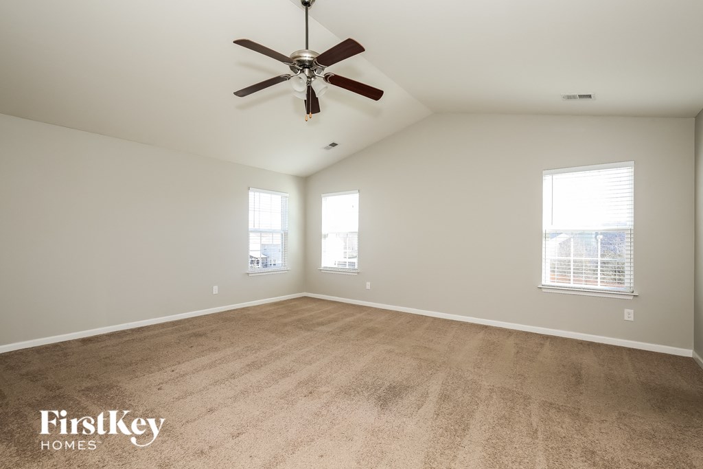A spacious room with a ceiling fan and carpeted floor.