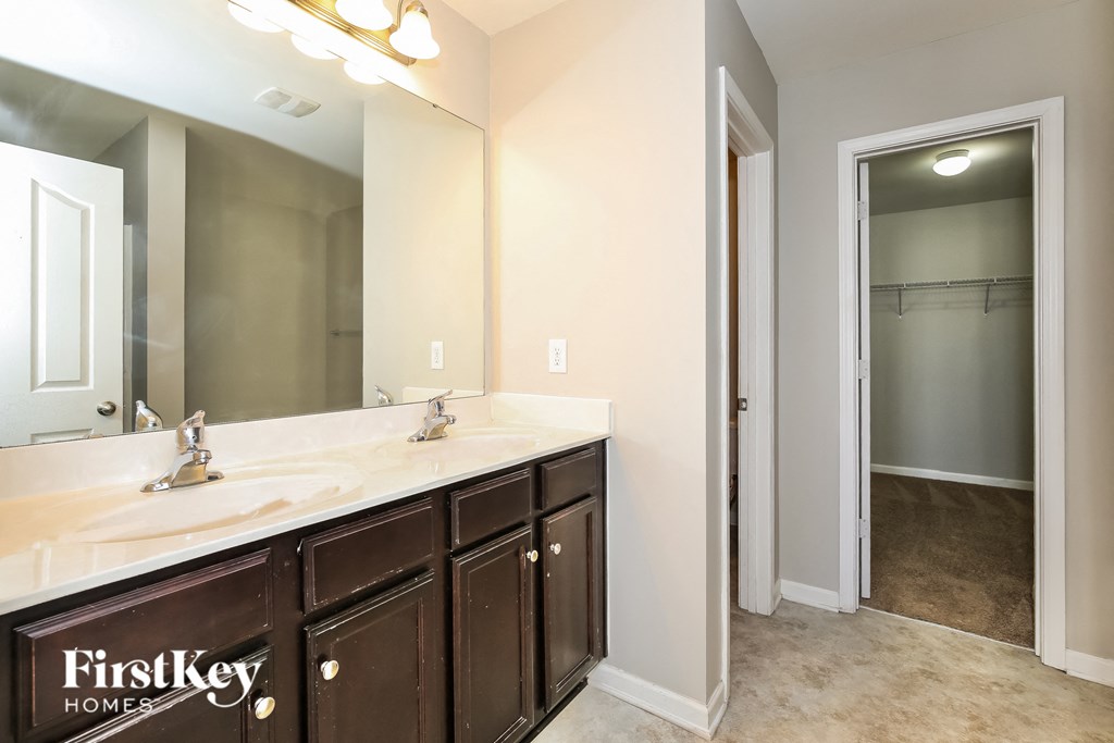 A bathroom with a double sink vanity and a mirror above it.