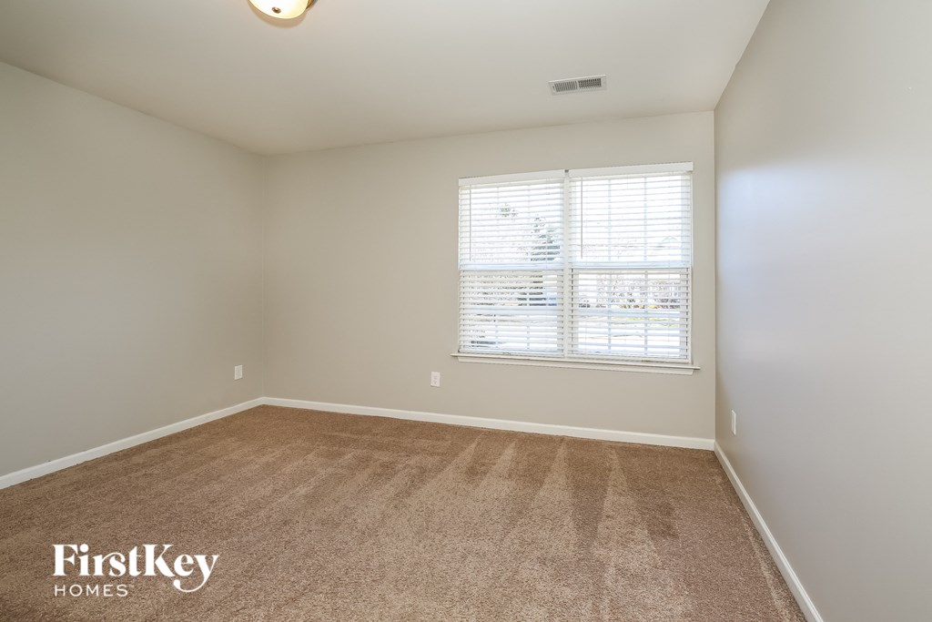 A room with a carpeted floor and a window with blinds.
