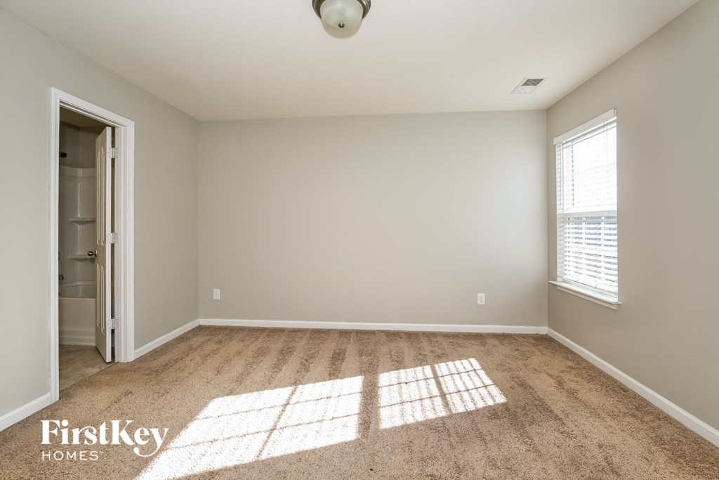 A room with a carpeted floor and a window letting in sunlight.