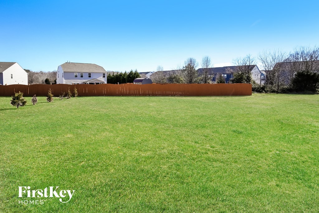 A grassy field with a fence and a house in the background.