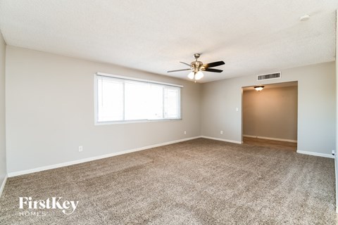 A spacious room with a carpeted floor and a ceiling fan.
