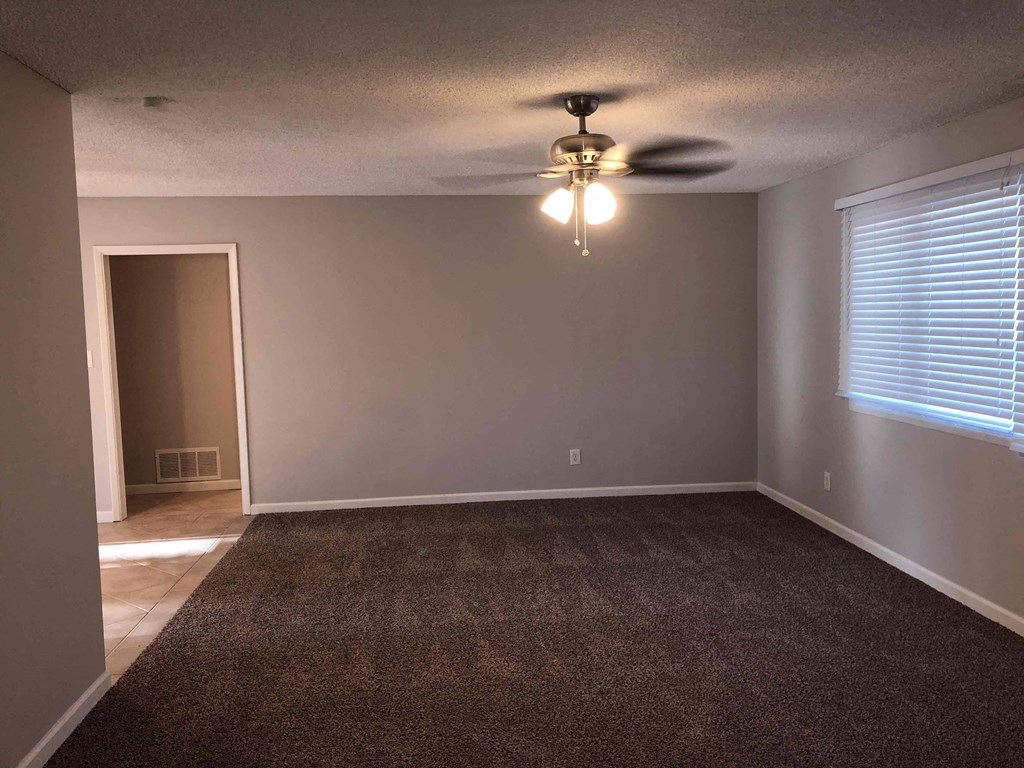 A room with a ceiling fan and a carpeted floor.
