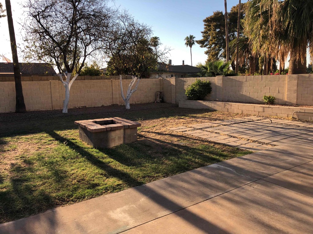 A concrete planter sits in the middle of a grassy yard.