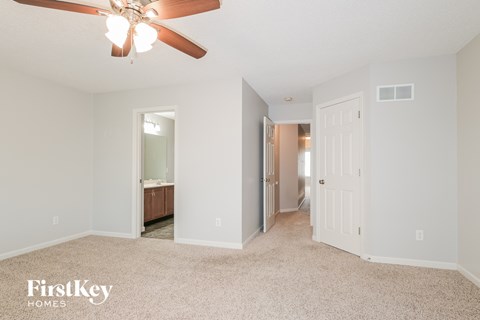 A spacious room with a ceiling fan and a carpeted floor.