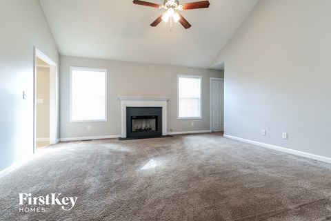 A spacious room with a fireplace and a ceiling fan.