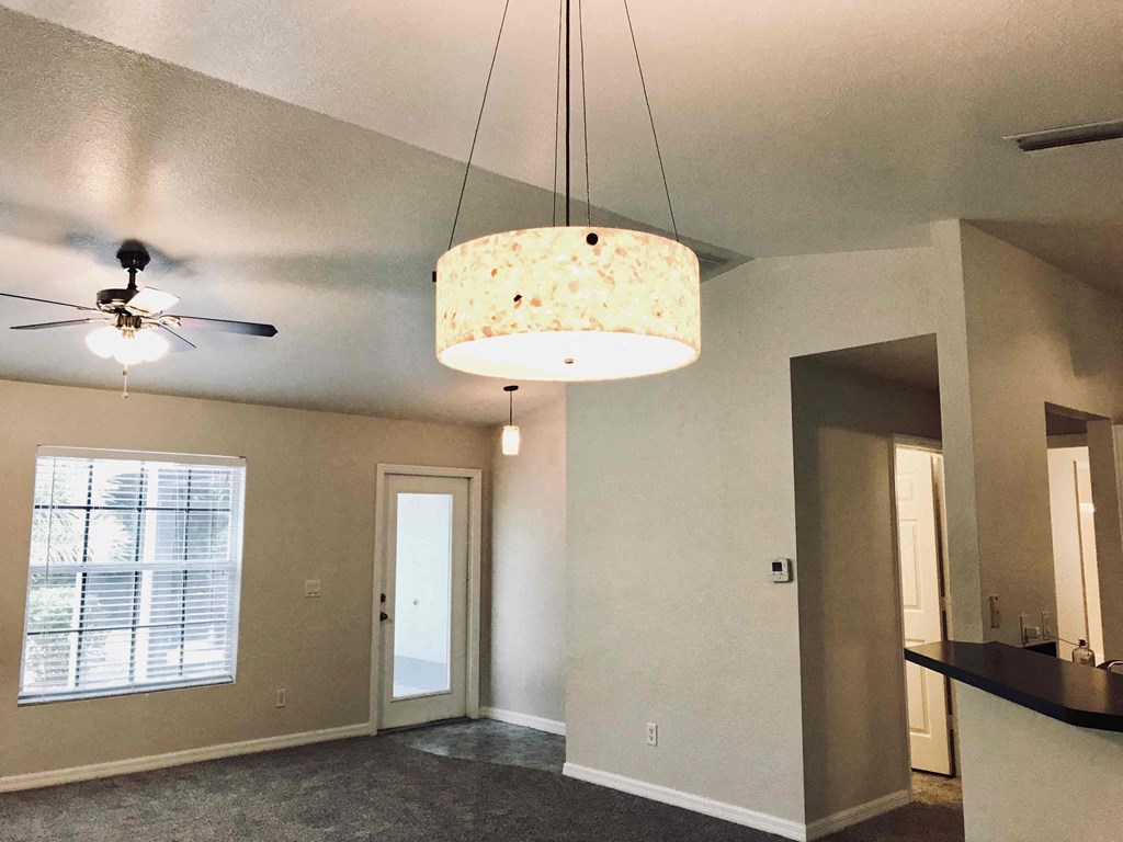A room with a ceiling fan and a hanging light fixture.