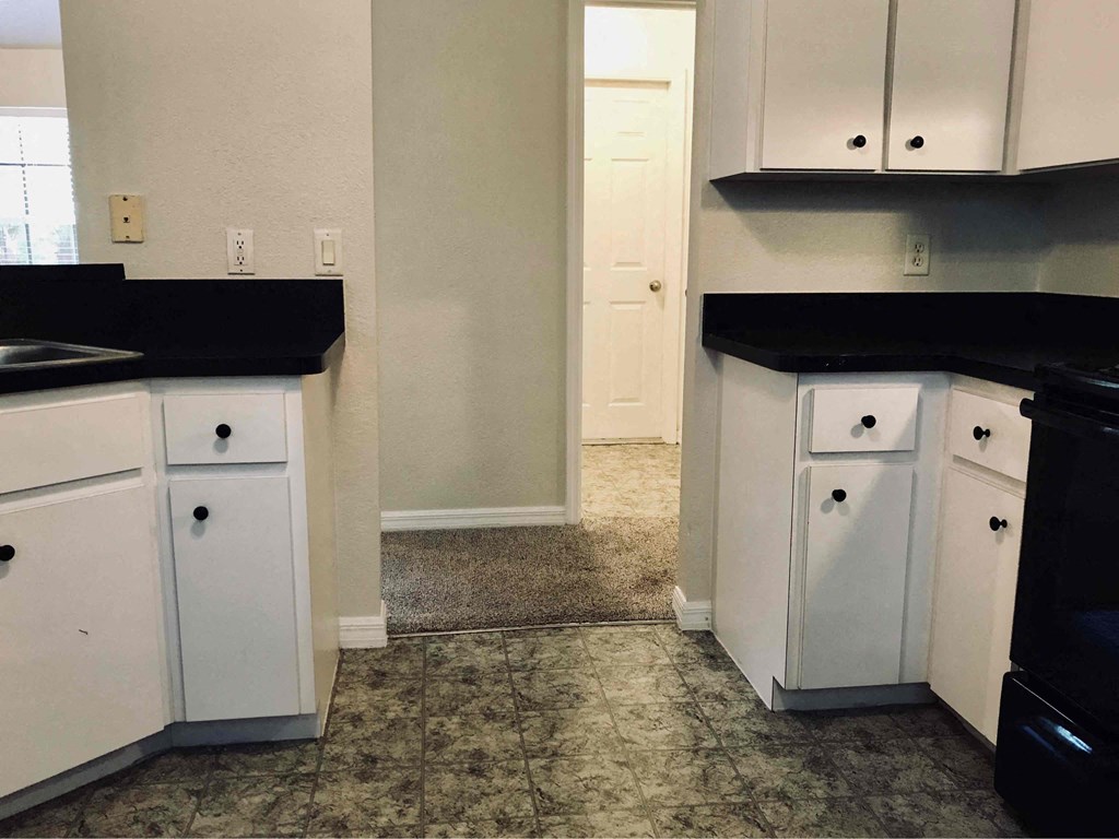 A kitchen with black countertops and white cabinets.