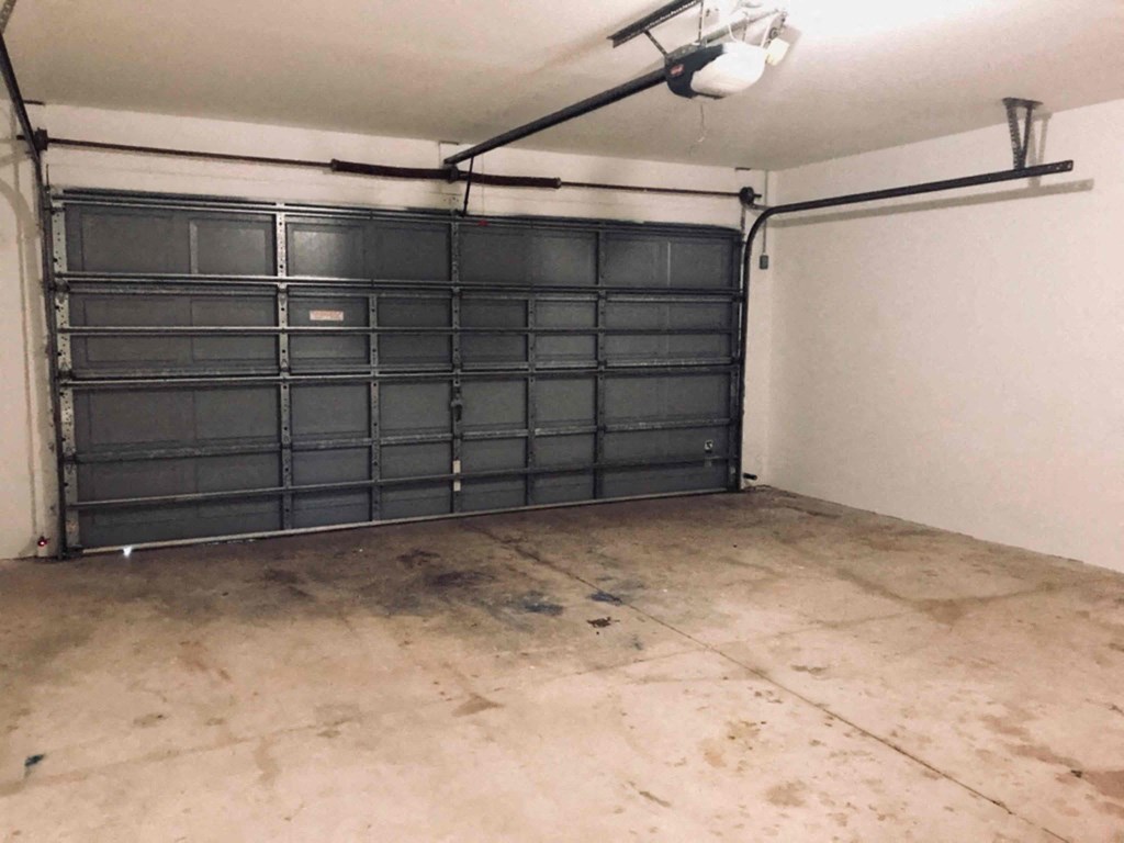 A large black garage door in a white wall garage.