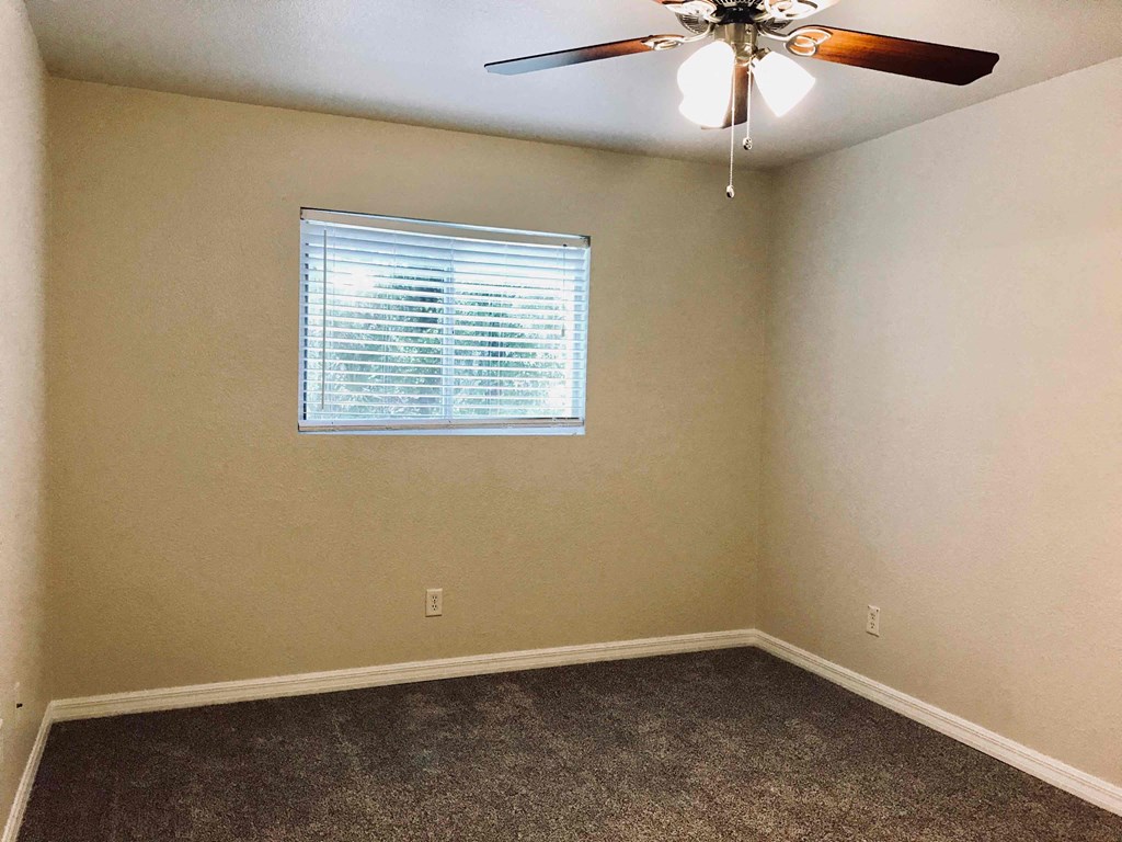 A room with a ceiling fan and a window with blinds.
