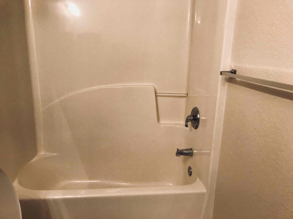 A white bathtub with a black faucet and a black handle.