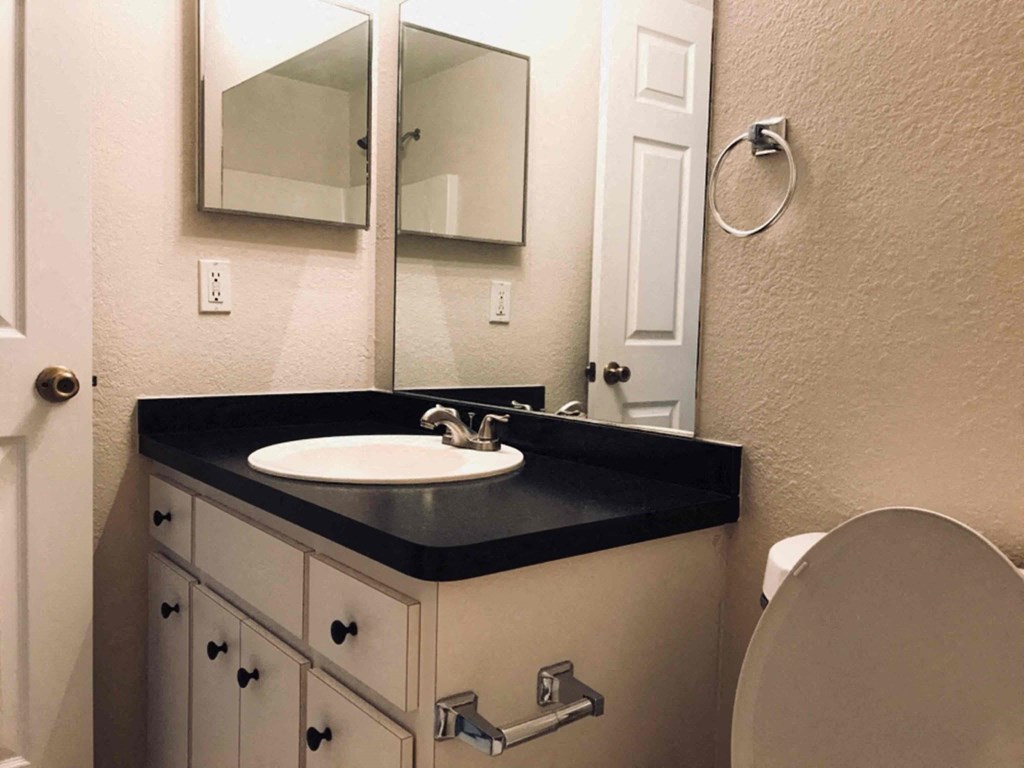 A bathroom with a sink, mirror, and toilet.