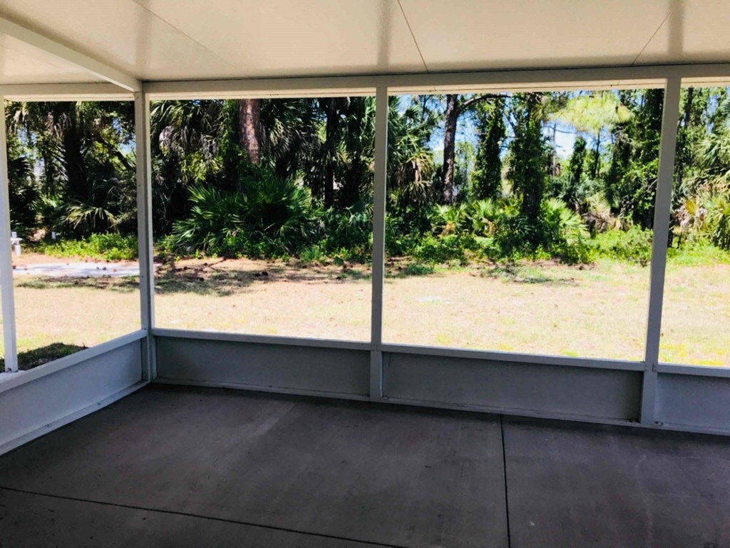 A room with a view of a forest through the windows.