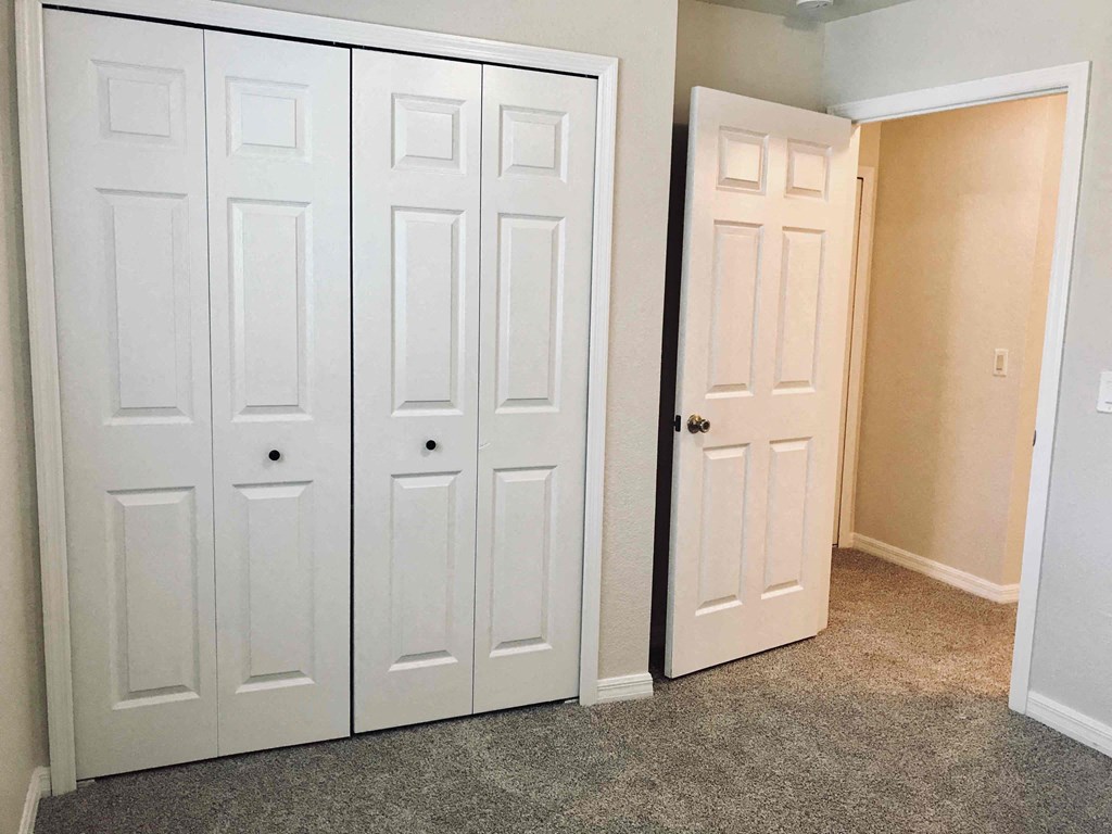 A white door is open to a room with a carpeted floor.