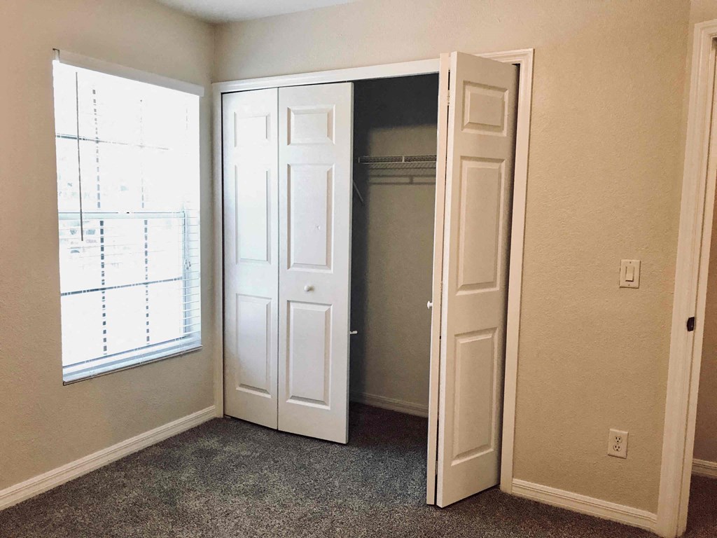 A room with a white door and a window with blinds.