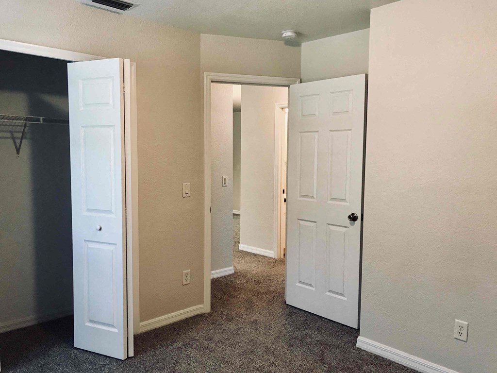 A room with two white doors and a grey carpet.