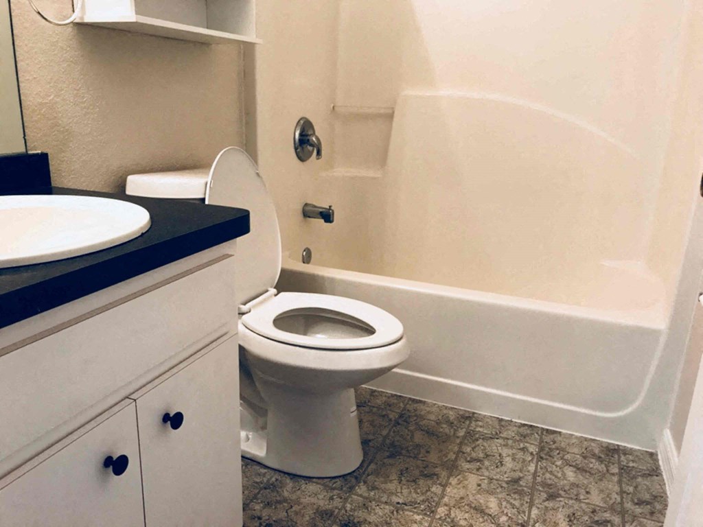 A white toilet sits in a bathroom next to a bathtub.