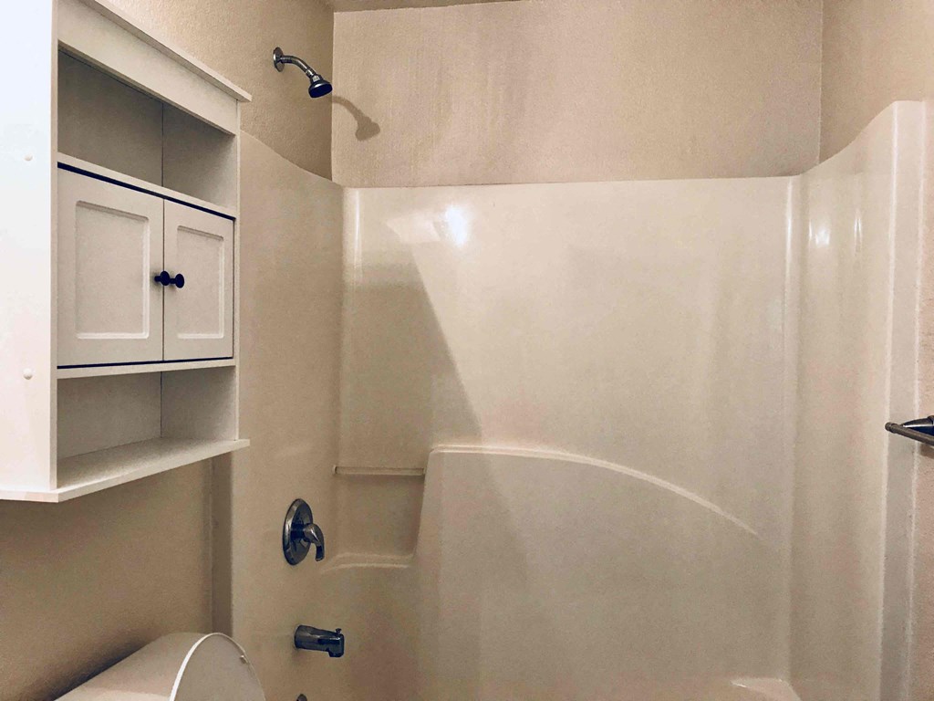 A white bathroom with a toilet and a shower.