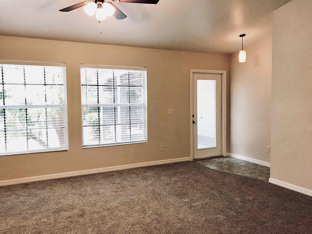 A room with a ceiling fan and carpeted floor.