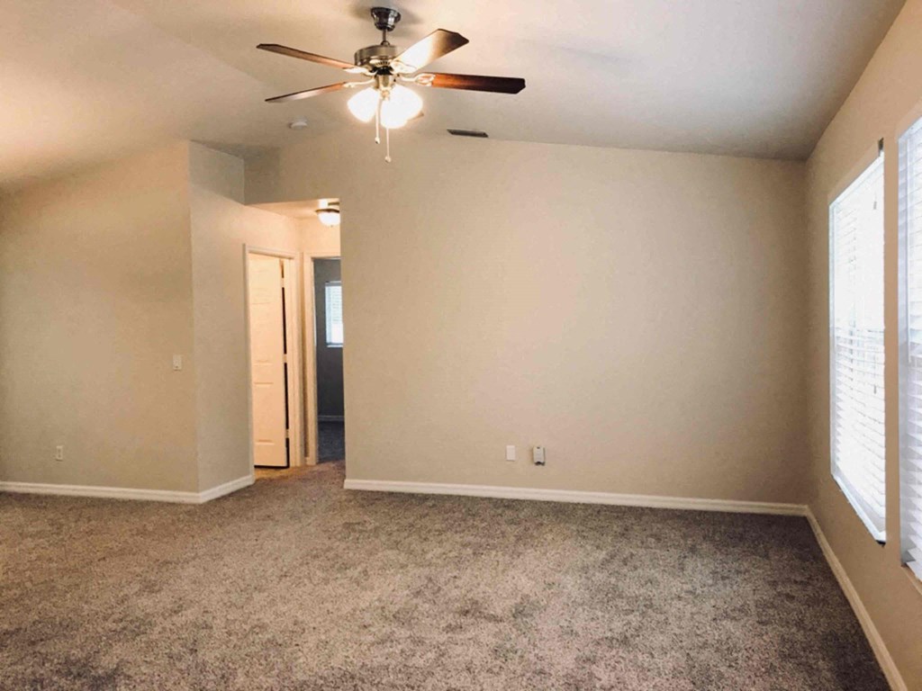 A room with a ceiling fan and carpeted floor.