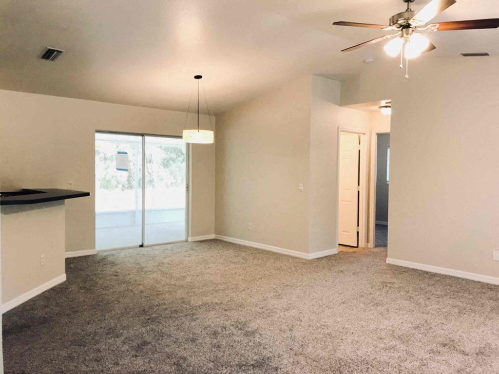 A room with a ceiling fan and carpeted floor.