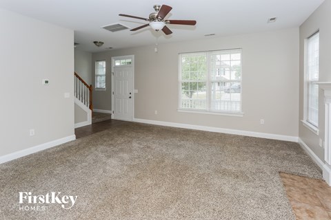 an empty living room with carpet and a ceiling fan