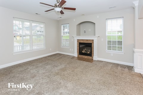 an empty living room with a fireplace and a ceiling fan