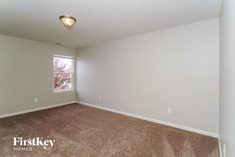 the upstairs bedroom with carpeting and a window