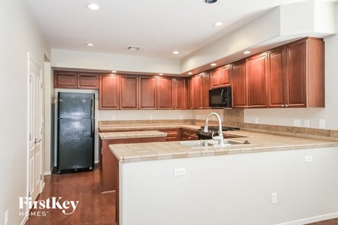 A kitchen with brown cabinets and a black fridge.