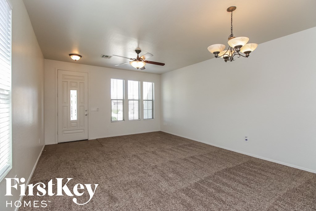 A spacious room with a carpeted floor and a ceiling fan.