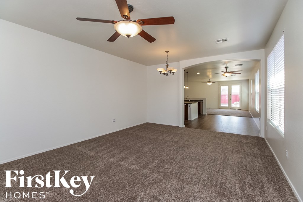 A spacious room with a ceiling fan and carpeted floor.