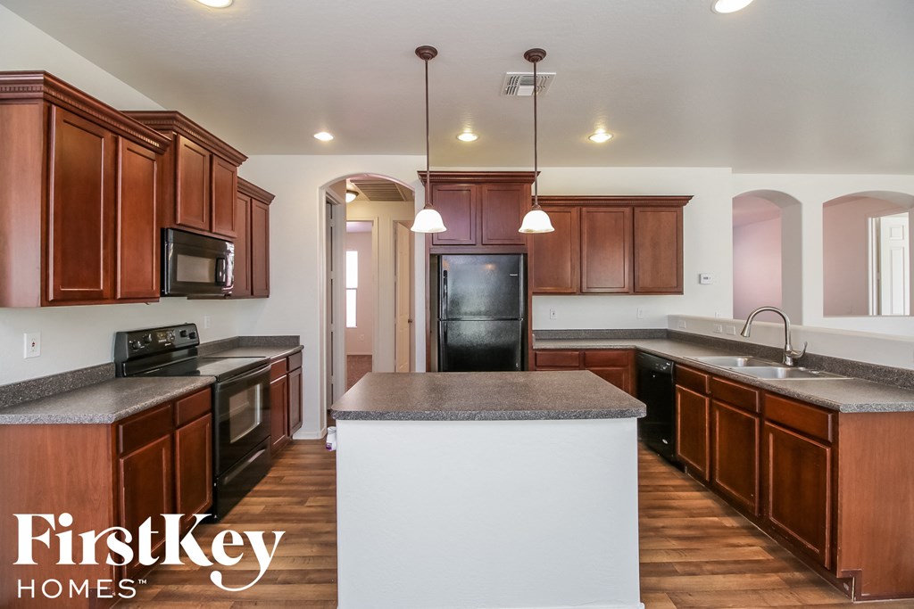 A kitchen with wooden cabinets and a black refrigerator.