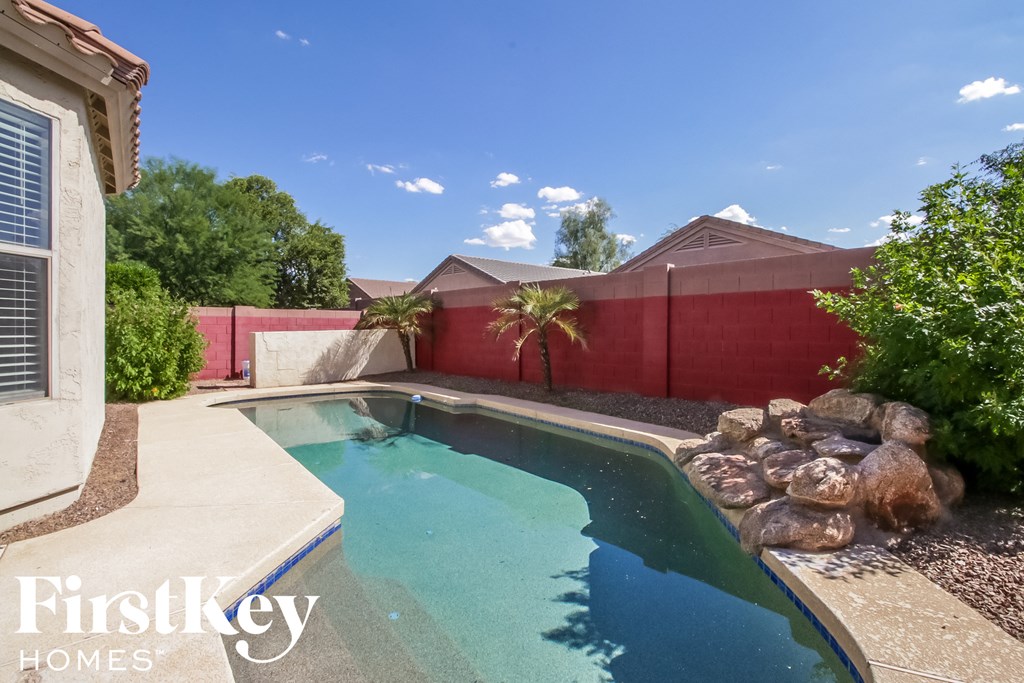 A swimming pool surrounded by rocks and a red wall.