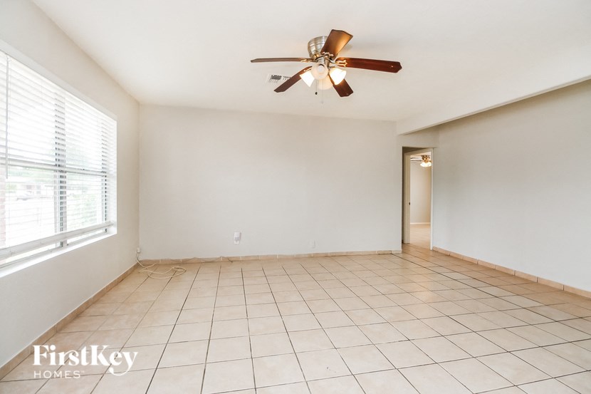A spacious room with a ceiling fan and tiled flooring.