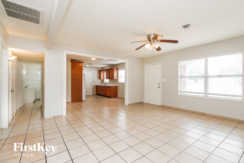 A spacious living room with a ceiling fan and tiled flooring.