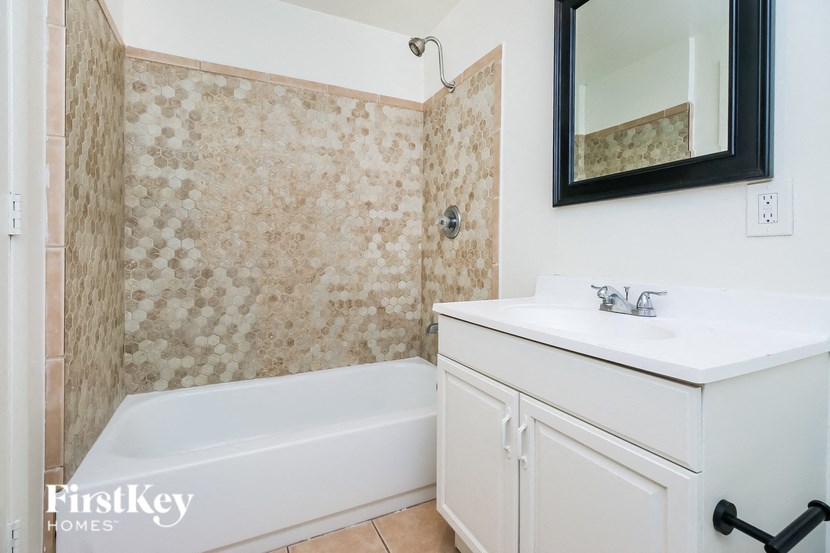 A white bathroom with a bathtub, sink, and mirror.