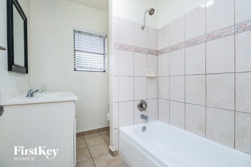 A white bathroom with a tub, sink, and window.