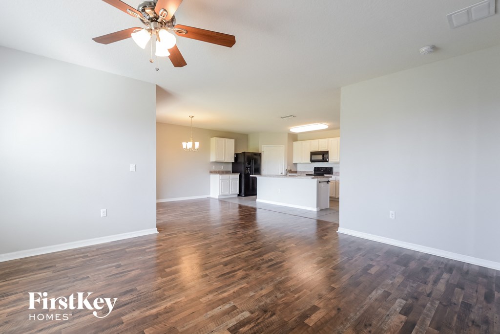 A spacious room with wooden flooring and a ceiling fan.