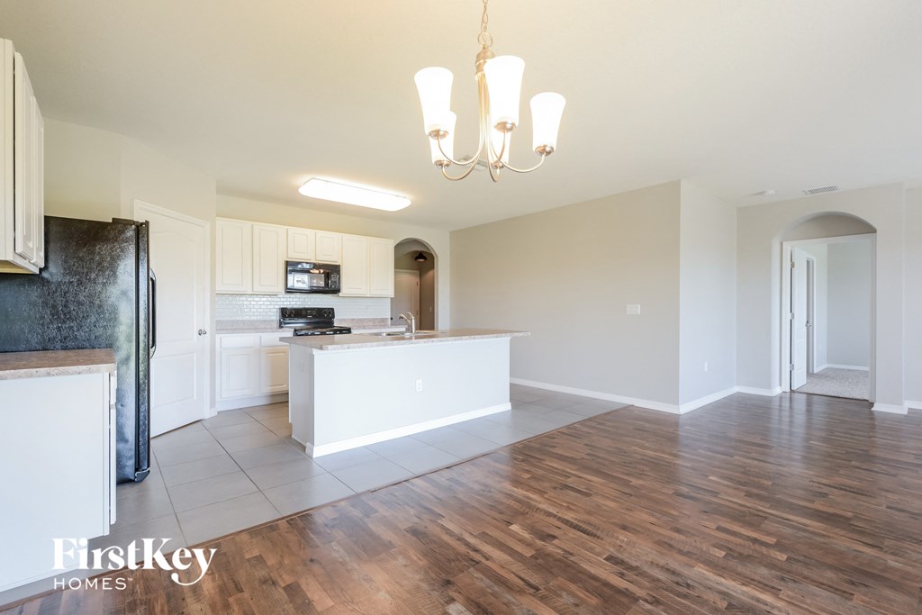 A kitchen with a refrigerator, a counter, and a chandelier.