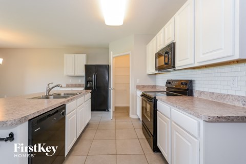 A kitchen with white cabinets and a black fridge.