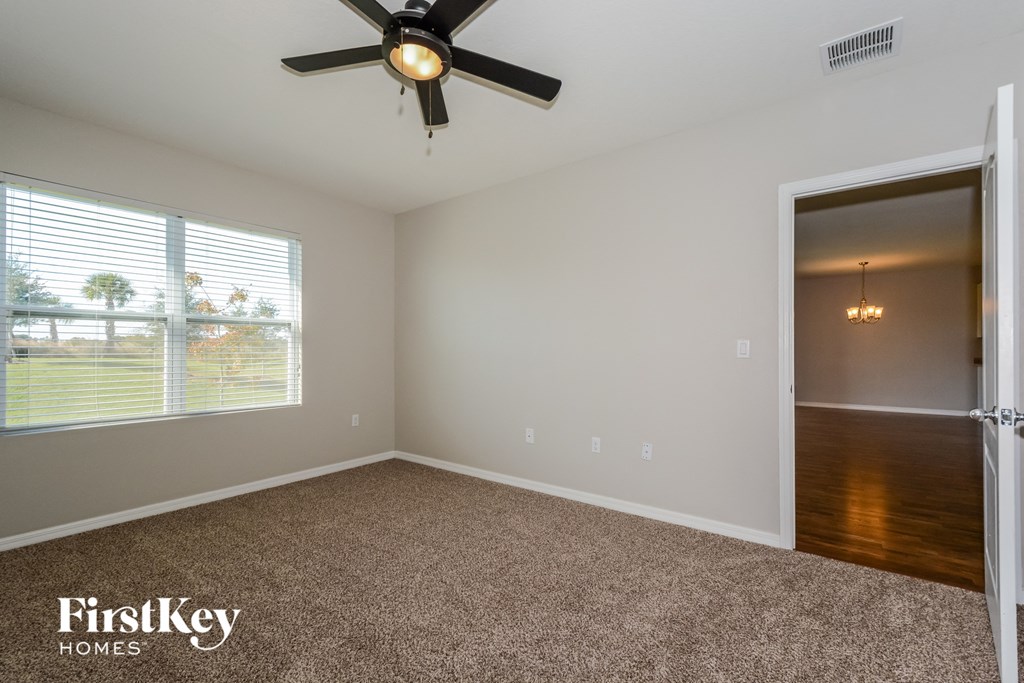 A room with a ceiling fan and a carpeted floor.