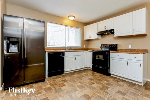 A kitchen with a tile floor and a refrigerator.