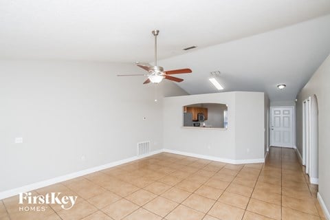 an empty living room with a ceiling fan and a tiled floor