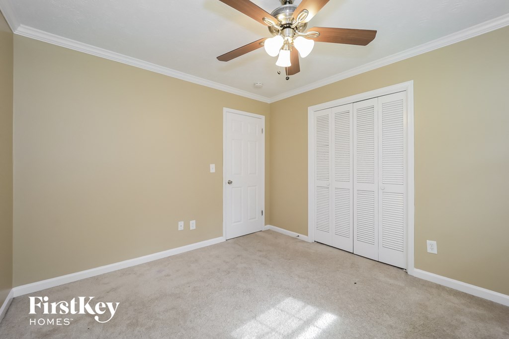 a empty living room with a ceiling fan and a closet