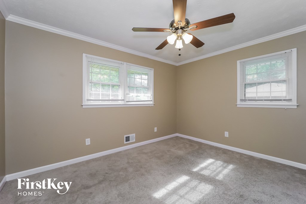 an empty room with a ceiling fan and two windows
