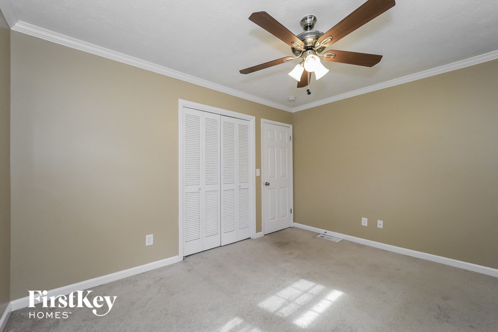 a empty living room with a ceiling fan and a closet