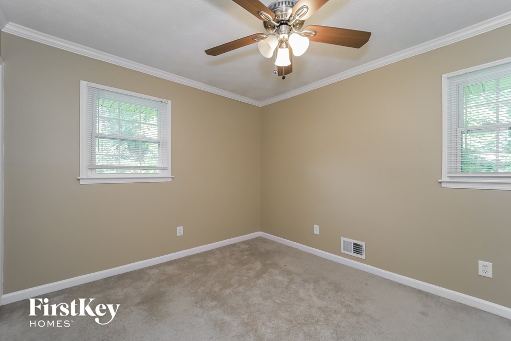 a empty bedroom with a ceiling fan and two windows