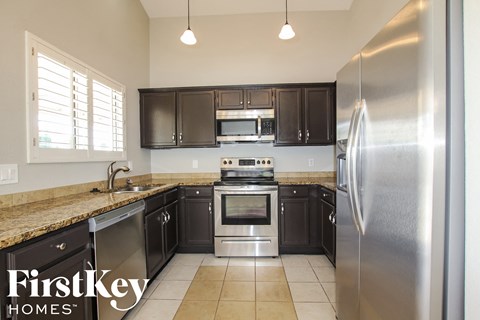 A kitchen with a stainless steel refrigerator and black cabinets.